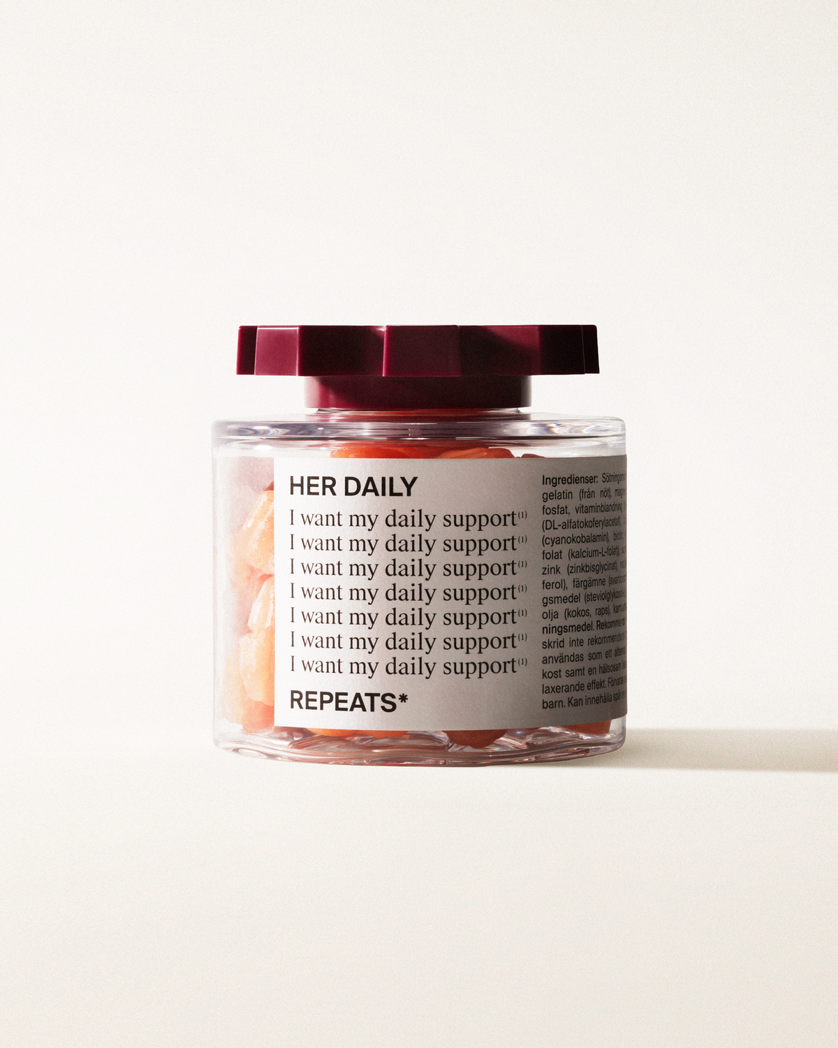 A transparent jar of REPEATS Her Daily, filled with orange gummies (supplements), sealed with a dark red, shaped lid. The jar has a white label featuring the text "Her Daily", repeated rows of "I want my daily support", and the brand Logo