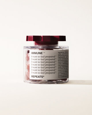 A transparent jar of REPEATS Immune, filled with red gummies (supplements), sealed with a dark red, shaped lid. The jar has a white label featuring the text 
