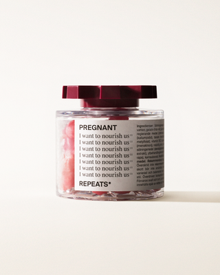 A transparent jar of REPEATS Pregnant, filled with pink gummies (supplements), sealed with a dark red, shaped lid. The jar has a white label featuring the text "Pregnant", repeated rows of "I want to nourish us", and the brand Logo