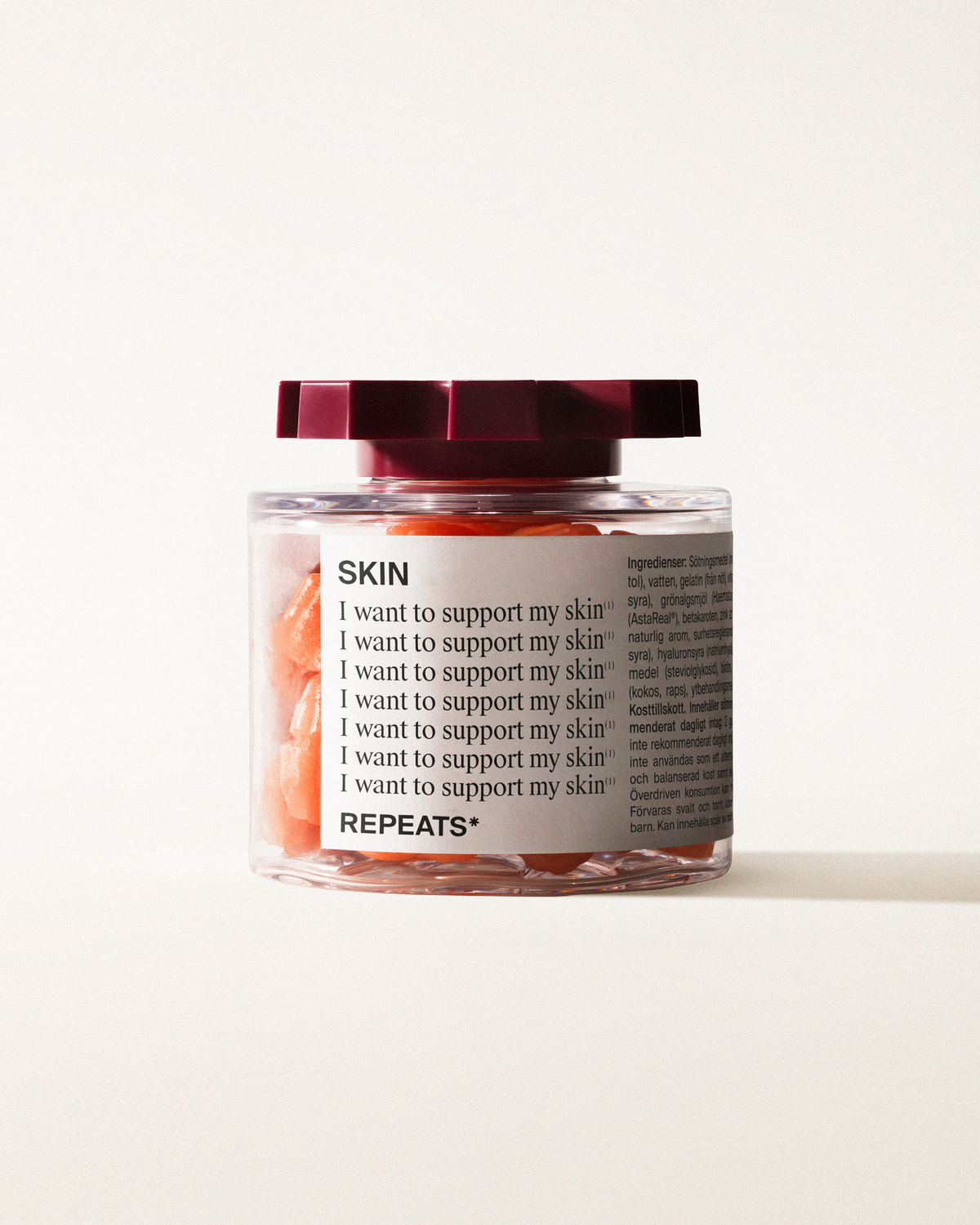 A transparent jar of REPEATS Her Daily, filled with orange gummies (supplements), sealed with a dark red, shaped lid. The jar has a white label featuring the text "Skin", repeated rows of "I want to support my skin", and the brand Logo
